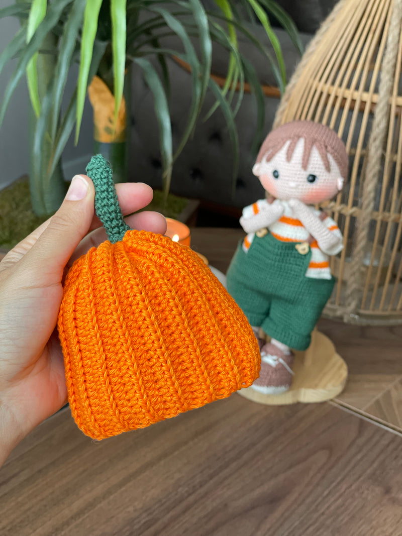 A handmade amigurumi crochet Boy With Pumpkin Hat, green overalls, and striped shirt. This customizable doll comes with a name label, perfect for fall or as an autumn gift.