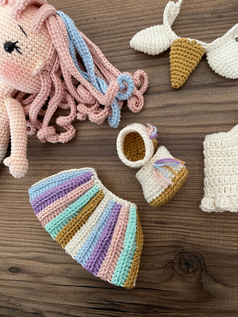 A handmade crocheted Unicorn Girl Doll with pastel rainbow dress, pink curly hair, and a golden horn. This amigurumi toy is customizable with a name on a leather label, perfect for nursery decor and personalized gifts.