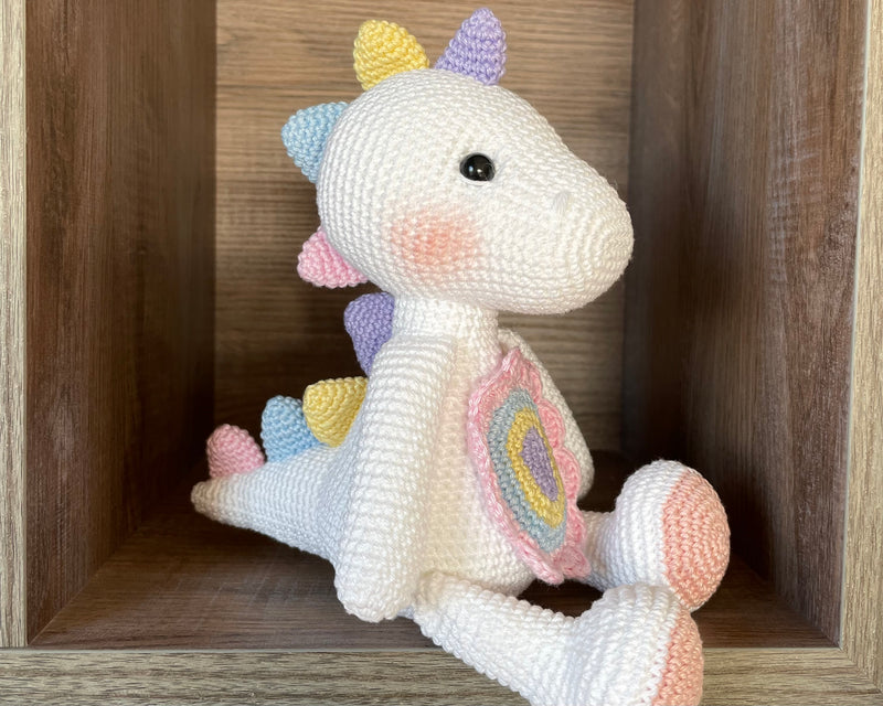 Handmade unicorn dinosaur toy crocheted with soft yarn in pastel colors, featuring customizable name on a leather label, perfect for kids and baby gifts.