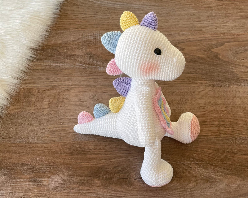 Handmade unicorn dinosaur toy crocheted with soft yarn in pastel colors, featuring customizable name on a leather label, perfect for kids and baby gifts.