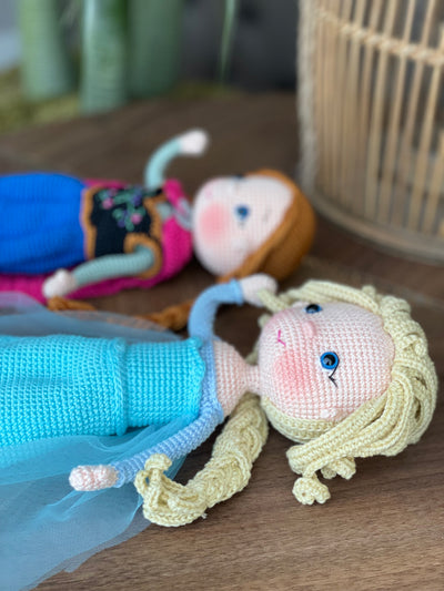 Handmade crocheted amigurumi dolls of Elsa and Anna, inspired by Frozen. Detailed with colorful outfits, perfect for custom name personalization or gifting.