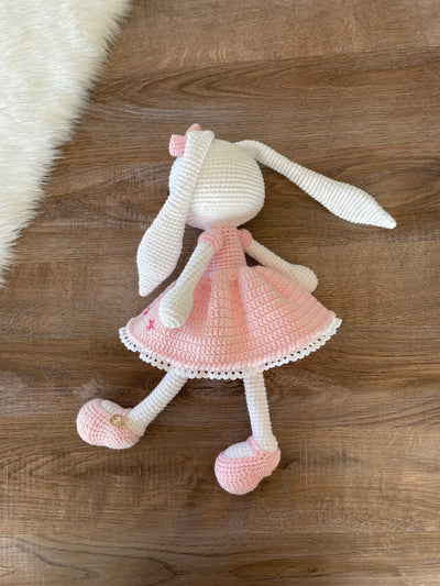 Handmade pink flower bunny rabbit toy crocheted using the amigurumi technique. Features a soft pink dress with floral details and is customizable with a name on a leather label. Perfect baby gift.