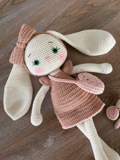 Handmade crocheted amigurumi bunny rabbit doll with a small mouse toy, dressed in pink, made of 100% cotton, customizable with a name on a leather label, perfect for nursery decor.