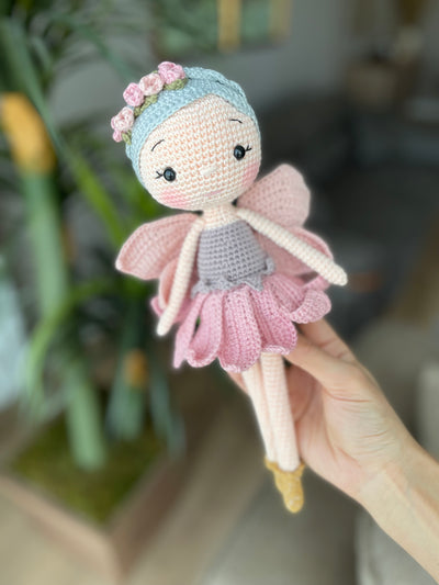 Handmade Fairy Doll with delicate wings, wearing a pink dress and floral headband, made with 100% cotton yarn, customizable with a name on a leather label.