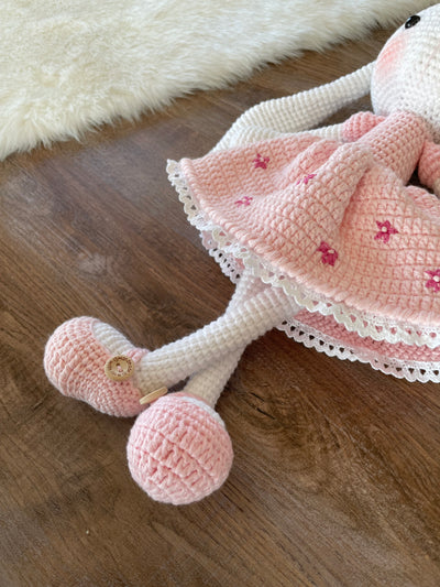 Handmade pink flower bunny rabbit toy crocheted using the amigurumi technique. Features a soft pink dress with floral details and is customizable with a name on a leather label. Perfect baby gift.