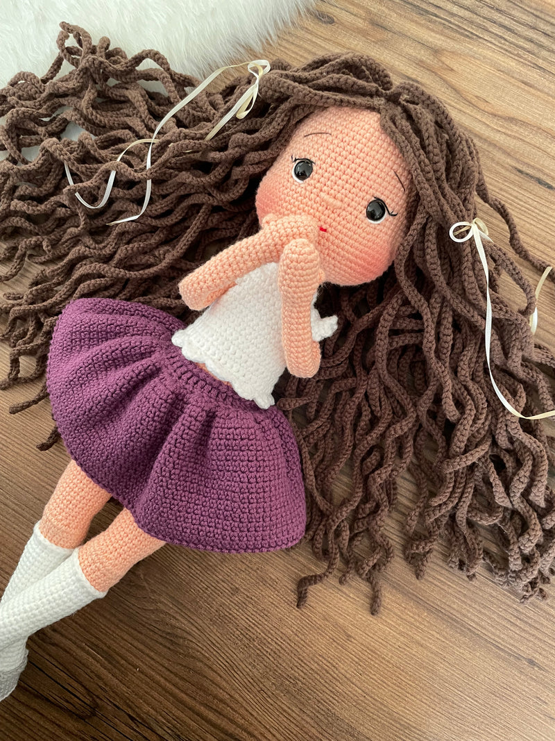 Handmade crocheted Purple Skirted Olivia Doll with long brown hair, a cute skirt, customizable with a name on a leather label. Ideal for nursery decor and as a personalized gift.