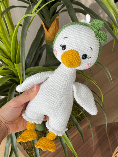 Handmade crocheted Duck Toy with a yellow beak and feet, customizable with a name on a leather label, crafted using amigurumi techniques. A perfect gift for kids or as nursery decor.