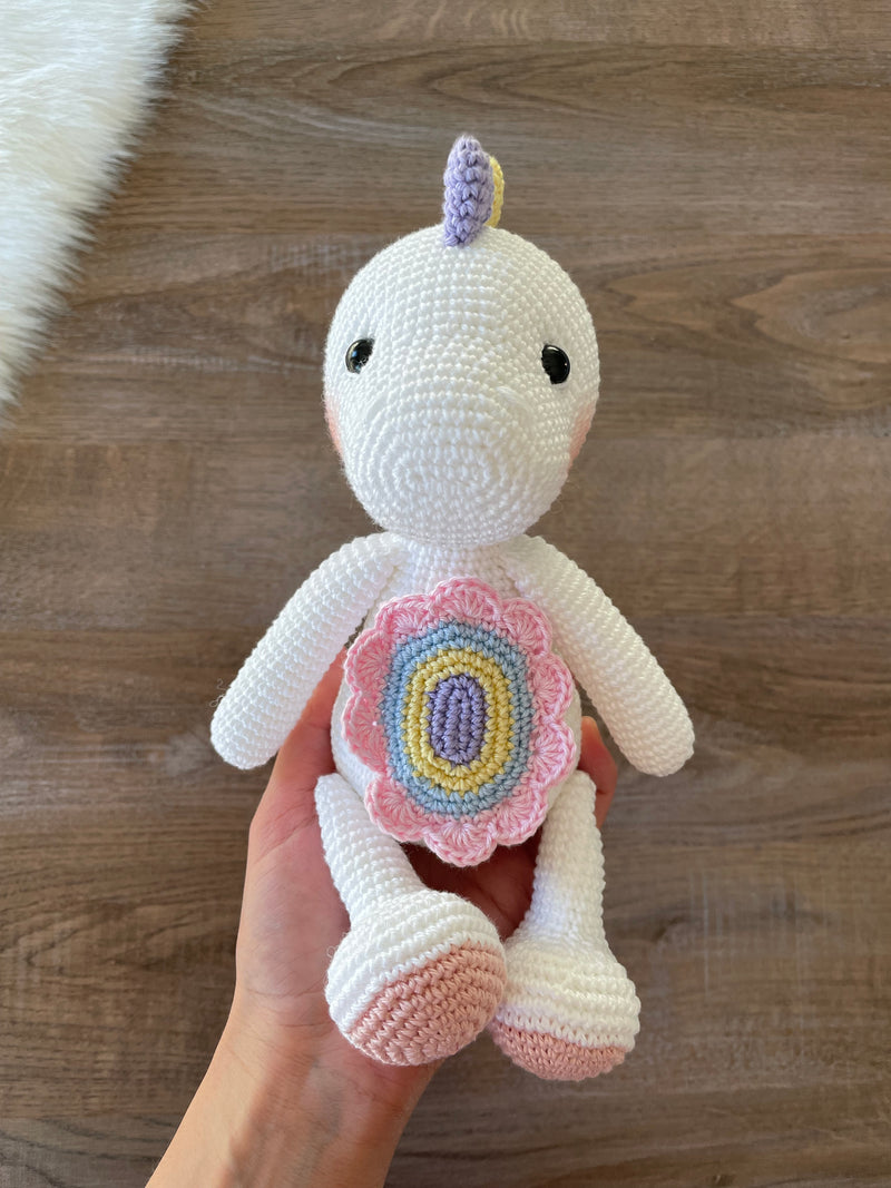 Handmade unicorn dinosaur toy crocheted with soft yarn in pastel colors, featuring customizable name on a leather label, perfect for kids and baby gifts.