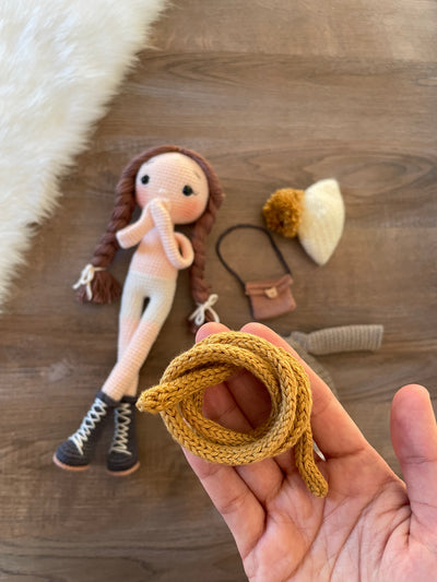 Handmade crochet Khaki Green Winter Girl Doll, featuring long braids, a cozy winter outfit, and personalized with a name on a leather label. Perfect gift for kids.