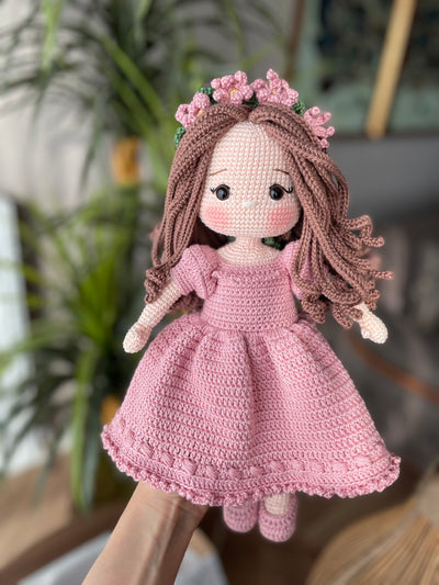 Handmade pink princess girl doll, crocheted using amigurumi technique. Features a beautiful dress and flower crown, customizable with a name on a leather label. Perfect for kids and collectors.