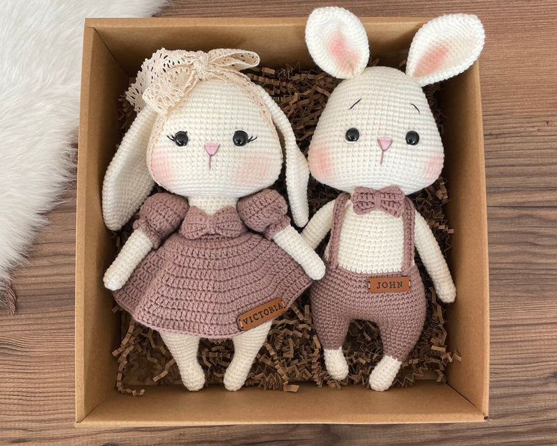 Handmade mink color bunny rabbit couple toy, lying inside a gift box, crocheted with amigurumi technique, personalized with names on leather labels, perfect for gifts and decor.