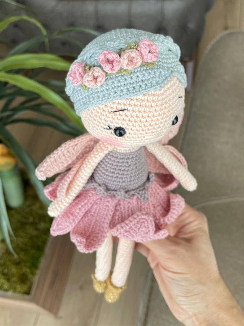 Handmade Fairy Doll with delicate wings, wearing a pink dress and floral headband, made with 100% cotton yarn, customizable with a name on a leather label.