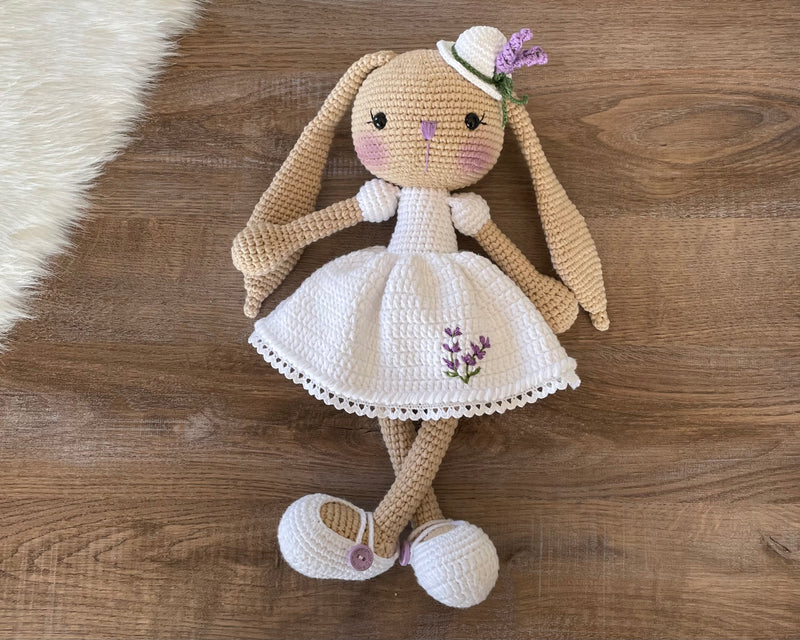 Handmade crocheted Lavender Flower Dressed Bunny Rabbit Toy, complete with a matching hat. This customizable toy includes a name on a leather label and is made using amigurumi techniques. Perfect for nurseries or as a personalized gift.