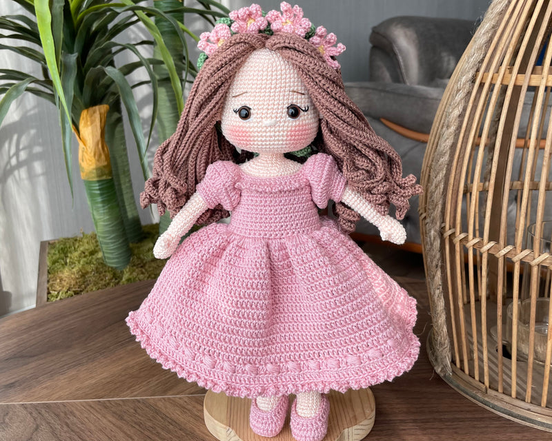 Handmade pink princess girl doll, crocheted using amigurumi technique. Features a beautiful dress and flower crown, customizable with a name on a leather label. Perfect for kids and collectors.