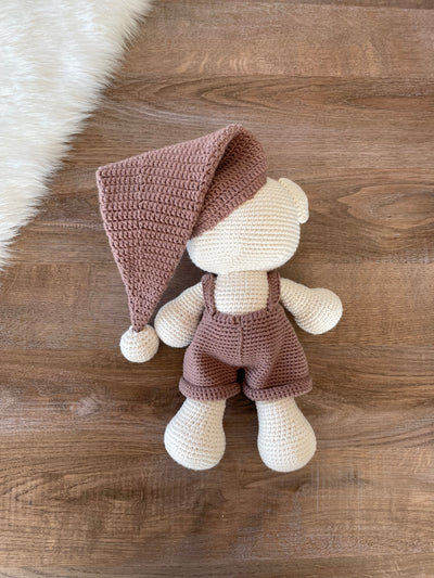 Handmade crocheted Sleeping Teddy Bear Toy in soft, neutral tones with a cozy hat and overalls, customizable with a name on a leather label. Perfect for bedtime cuddles and nursery decor.