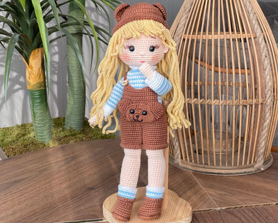 Handmade overall girl doll, crocheted using the amigurumi technique, dressed in overalls and personalized with a name on a leather label, perfect for gifts and decor.