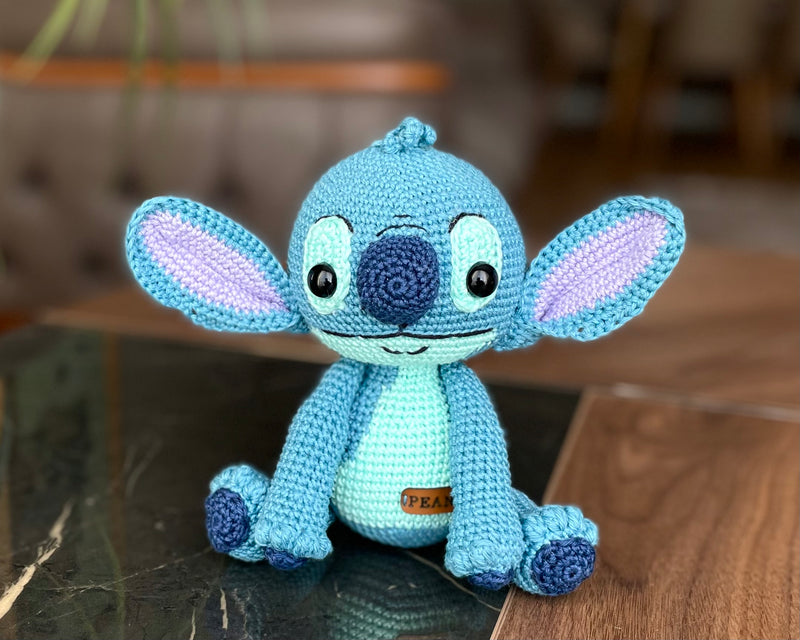 Handmade crochet Stitch Toy, amigurumi plush with a custom name on a leather label. Perfect as a personalized gift for kids, featuring a blue alien design.