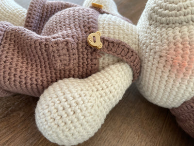 Handmade crocheted Sleeping Teddy Bear Toy in soft, neutral tones with a cozy hat and overalls, customizable with a name on a leather label. Perfect for bedtime cuddles and nursery decor.