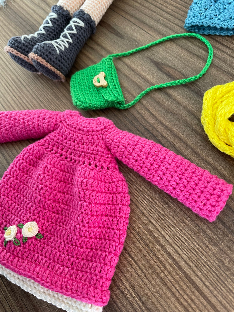 Handmade crocheted Magenta Winter Girl Doll featuring a magenta dress, flower detail, and a cute braided hairstyle. Customizable with a name on a leather label, made using amigurumi techniques. Perfect as a personalized gift or nursery decor.