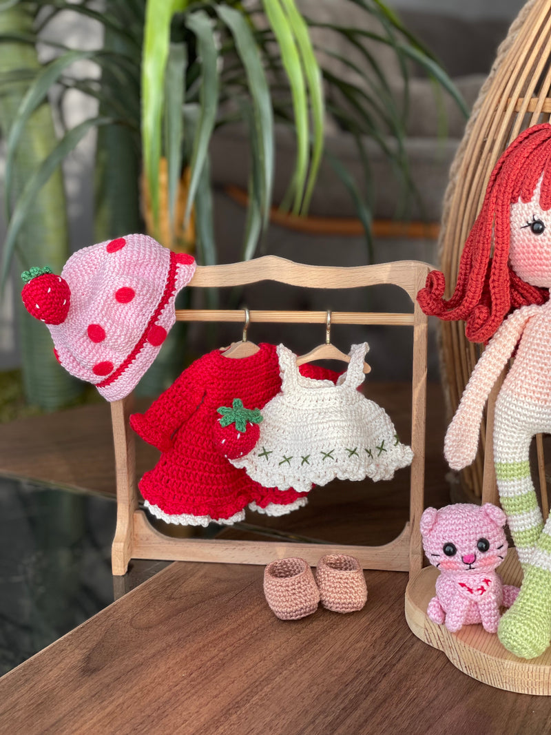 Handmade strawberry shortcake crochet doll with red hair, wearing a strawberry-themed outfit. Features a pink hat with red polka dots, red dress with white apron, and striped stockings. Perfect for children and collectors.