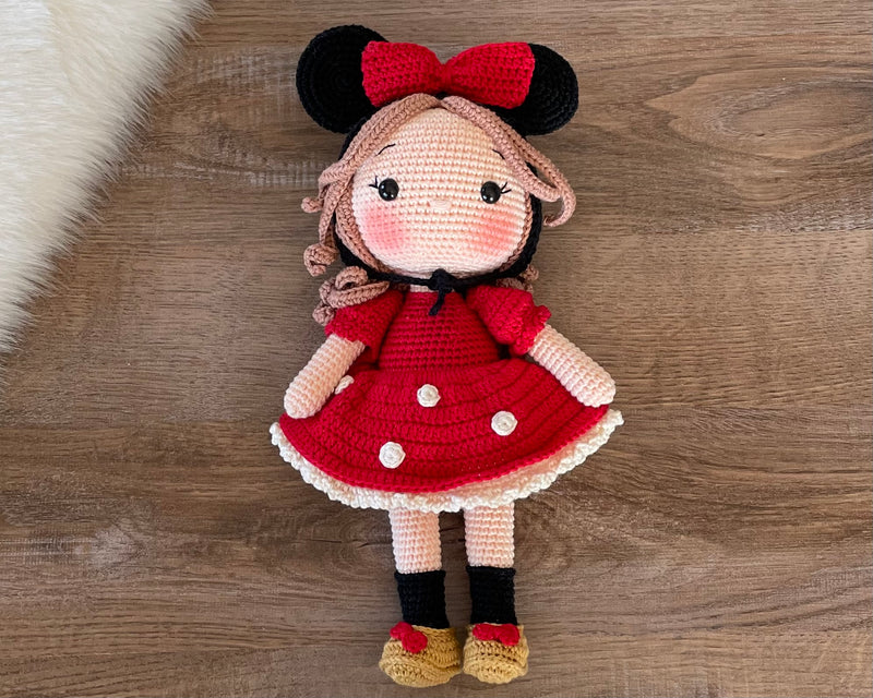 Handmade crochet Micky Girl Doll with a red dress, black ears, and a red bow. This amigurumi doll is customizable with a name on a leather label, perfect for personalized gifts.