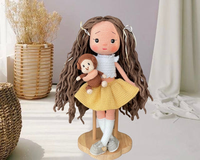 Handmade crocheted Yellow Skirted Olivia Doll with long brown hair, a cute skirt, and a tiny monkey, customizable with a name on a leather label. Ideal for nursery decor and as a personalized gift.