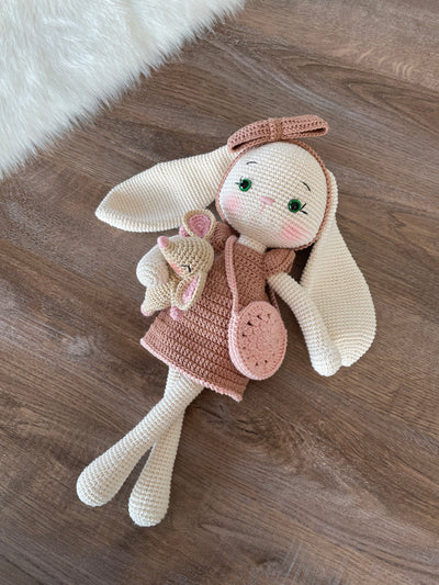 Handmade crocheted amigurumi bunny rabbit doll with a small mouse toy, dressed in pink, made of 100% cotton, customizable with a name on a leather label, perfect for nursery decor.