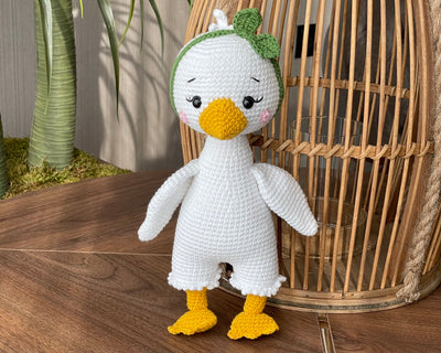 Handmade crocheted Duck Toy with a yellow beak and feet, customizable with a name on a leather label, crafted using amigurumi techniques. A perfect gift for kids or as nursery decor.