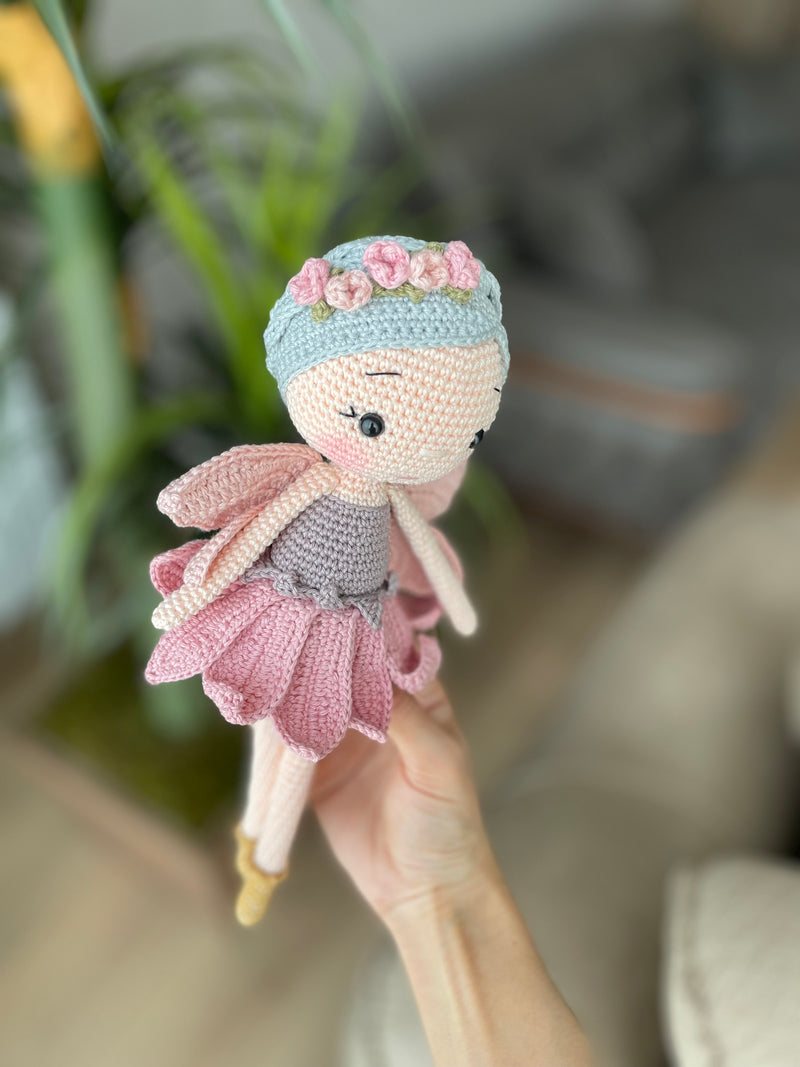 Handmade Fairy Doll with delicate wings, wearing a pink dress and floral headband, made with 100% cotton yarn, customizable with a name on a leather label.