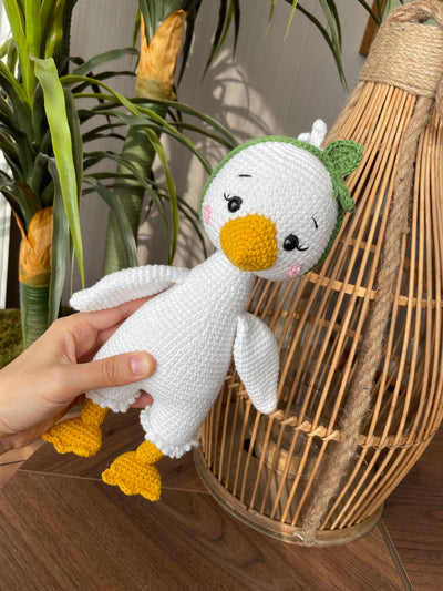 Handmade crocheted Duck Toy with a yellow beak and feet, customizable with a name on a leather label, crafted using amigurumi techniques. A perfect gift for kids or as nursery decor.