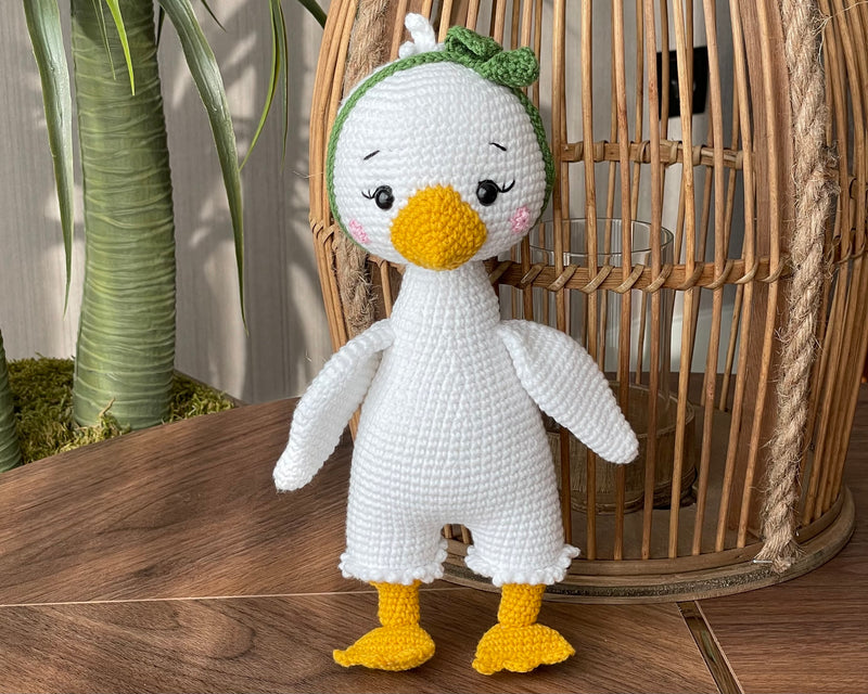 Handmade crocheted Duck Toy with a yellow beak and feet, customizable with a name on a leather label, crafted using amigurumi techniques. A perfect gift for kids or as nursery decor.