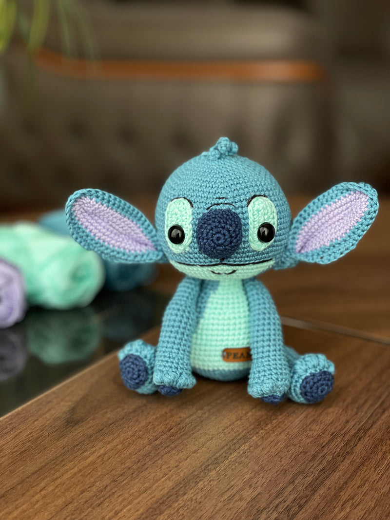 Handmade crochet Stitch Toy, amigurumi plush with a custom name on a leather label. Perfect as a personalized gift for kids, featuring a blue alien design.