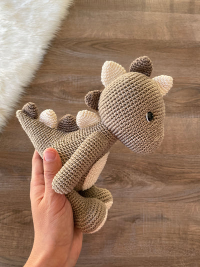 Handmade crochet dinosaur toy in shades of brown and beige, crafted with 100% cotton yarns. This amigurumi dinosaur is customizable with a name on a leather label, perfect for eco-friendly, personalized baby gifts and nursery decor.