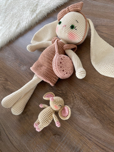 Handmade crocheted amigurumi bunny rabbit doll with a small mouse toy, dressed in pink, made of 100% cotton, customizable with a name on a leather label, perfect for nursery decor.