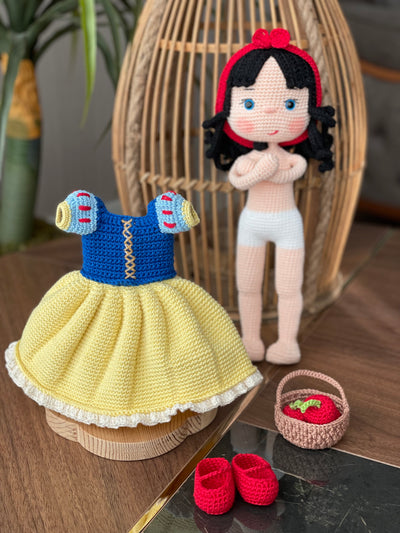 Handmade Snow White Doll wearing a classic yellow dress with a blue bodice, holding a basket of apples, made with 100% cotton yarn, customizable with a name on a leather label.