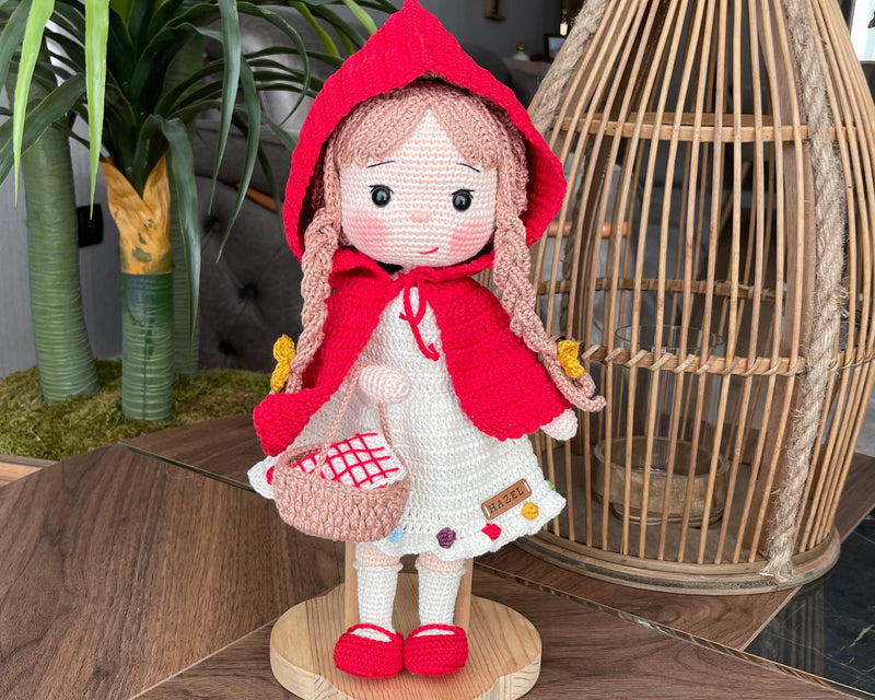 Handmade crochet Little Red Riding Hood doll, inspired by the classic fairytale, featuring a red cape, basket, and customizable name on a leather label. Perfect for kids and collectors.