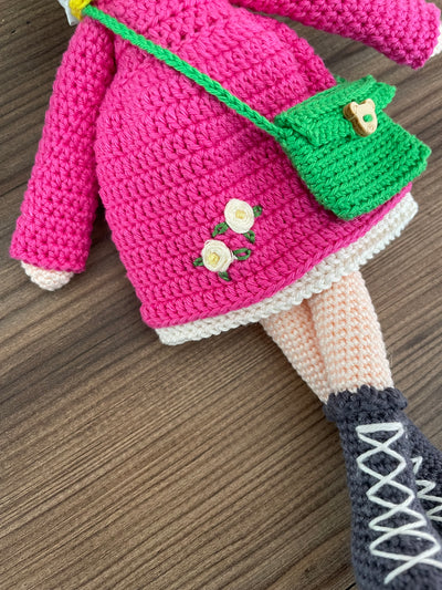 Handmade crocheted Magenta Winter Girl Doll featuring a magenta dress, flower detail, and a cute braided hairstyle. Customizable with a name on a leather label, made using amigurumi techniques. Perfect as a personalized gift or nursery decor.