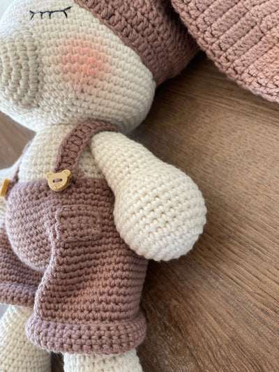 Handmade crocheted Sleeping Teddy Bear Toy in soft, neutral tones with a cozy hat and overalls, customizable with a name on a leather label. Perfect for bedtime cuddles and nursery decor.