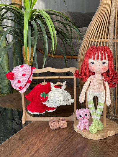 Handmade strawberry shortcake crochet doll with red hair, wearing a strawberry-themed outfit. Features a pink hat with red polka dots, red dress with white apron, and striped stockings. Perfect for children and collectors.