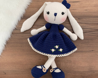 Handmade Navy Blue Dressed Bunny Rabbit Toy crocheted with amigurumi technique, featuring a cute navy blue dress with embroidered flower details and customizable name on a leather label. Perfect for kids and baby gifts.