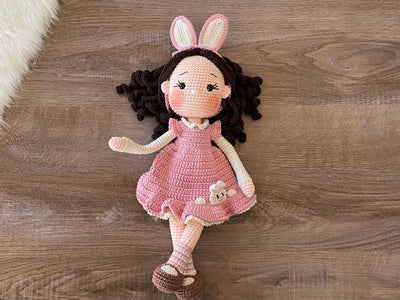 Handmade Pink Bunny Girl Doll with bunny ears, wearing a pink dress with bunny details, made with 100% cotton yarn, customizable with a name on a leather label, perfect for unique girl gifts and imaginative play.