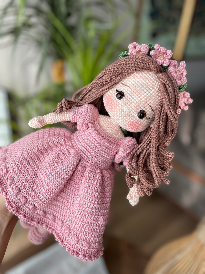 Handmade pink princess girl doll, crocheted using amigurumi technique. Features a beautiful dress and flower crown, customizable with a name on a leather label. Perfect for kids and collectors.