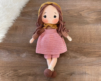 Handmade village girl doll crocheted using the amigurumi technique. Dressed in a rustic pink outfit with a bonnet, this personalized doll features a custom name on a leather label. Perfect for collectors and kids.