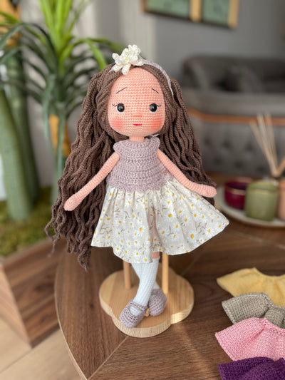 Handmade crocheted Daisy Dressed Olivia Doll with long brown hair and a floral dress, customizable with a name on a leather label. Perfect for nursery decor and as a personalized gift.