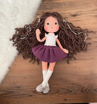 Handmade crocheted Purple Skirted Olivia Doll with long brown hair, a cute skirt, customizable with a name on a leather label. Ideal for nursery decor and as a personalized gift.