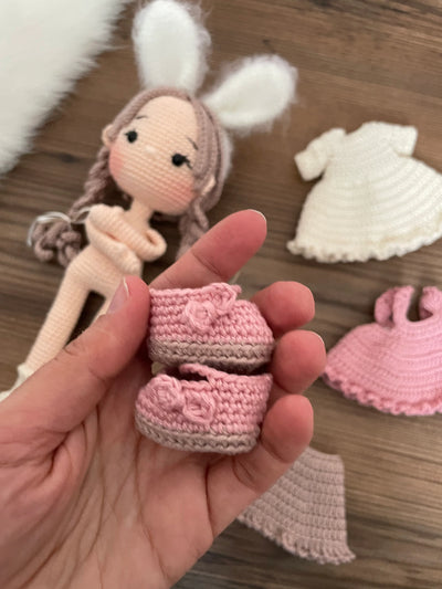 A handmade crocheted Rabbit Girl Doll with a pink dress, braided hair, and soft bunny ears. This amigurumi toy is customizable with a name on a leather label, making it a perfect choice for nursery decor and personalized gifts.