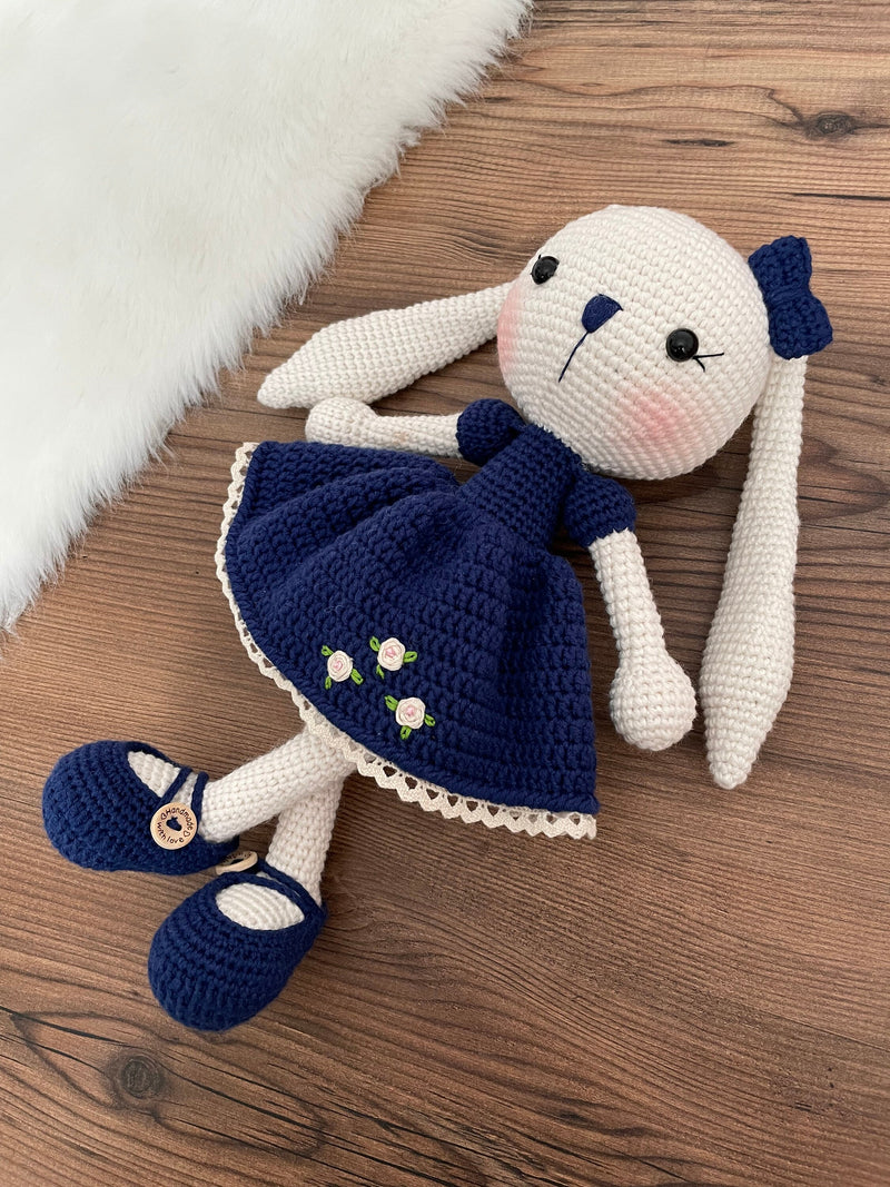 Handmade Navy Blue Dressed Bunny Rabbit Toy crocheted with amigurumi technique, featuring a cute navy blue dress with embroidered flower details and customizable name on a leather label. Perfect for kids and baby gifts.