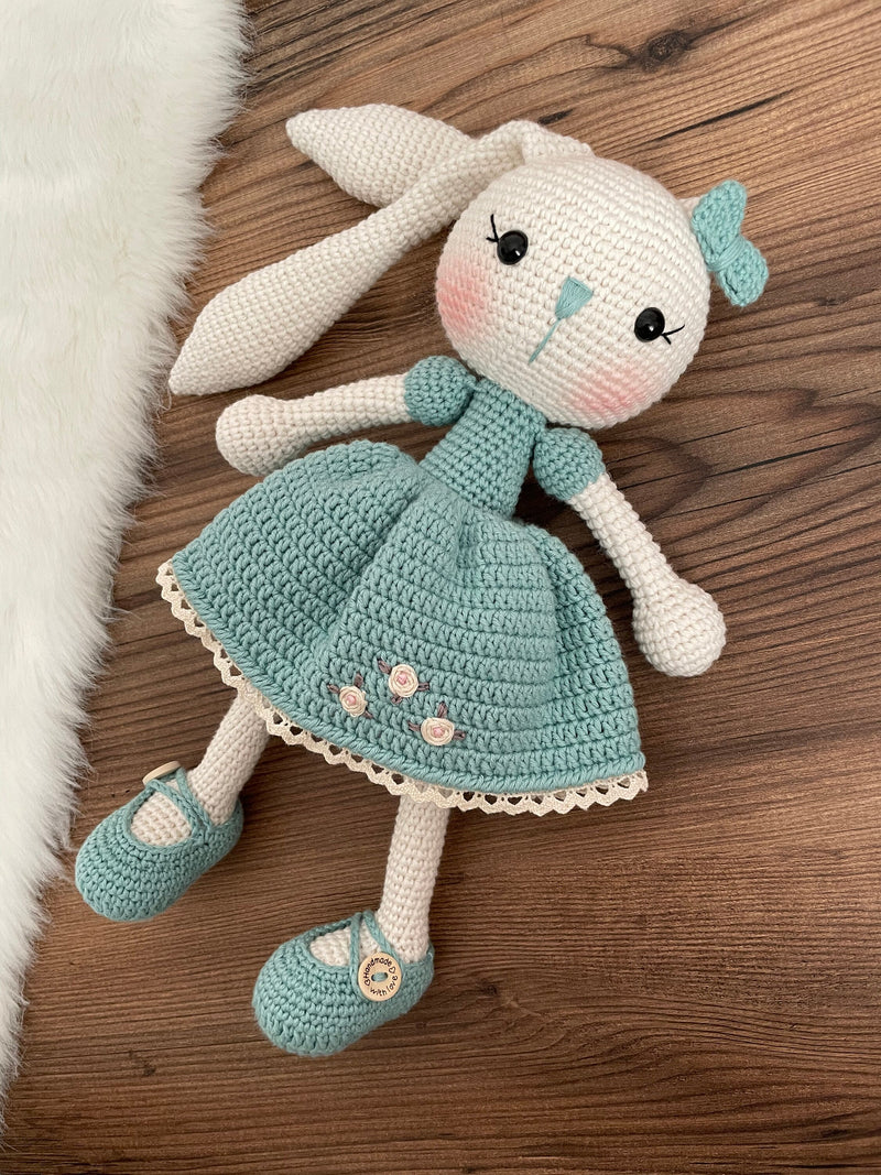 Handmade Sage Green Dressed Bunny Rabbit Toy crocheted with amigurumi technique, featuring a cute sage green dress with embroidered flower details and customizable name on a leather label. Perfect for kids and baby gifts.