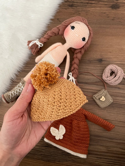 Handmade crochet winter girl doll in a brick-colored dress and hat, crafted with 100% cotton yarns. This amigurumi doll is customizable with a name on a leather label, making it a perfect, personalized gift for children and nursery decor.