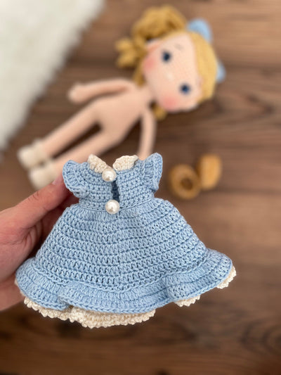 Handmade Blue Nina Doll with blonde hair, wearing a blue dress and a matching bow, made with 100% cotton yarn, customizable with a name on a leather label.